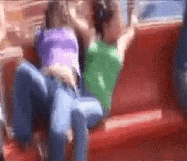 two women are sitting on a red couch .