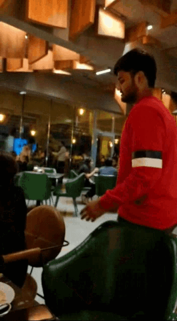 a man in a red sweater is standing in front of a restaurant