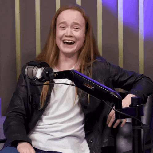 a woman laughs while sitting in front of a microphone that says jvc on the arm