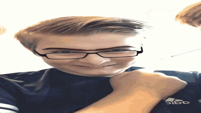 a boy wearing glasses and a shirt that says adidas on it