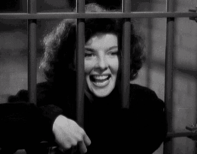 a black and white photo of a woman behind bars
