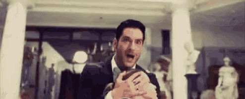 a man in a suit and tie is holding a statue in his hands in a room .