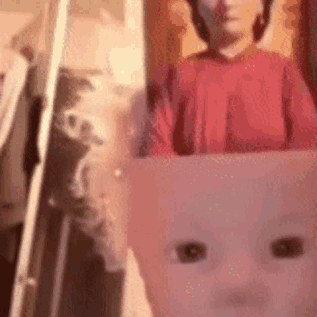a close up of a baby 's face with a person behind it .