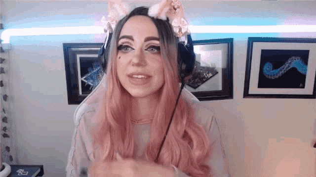 a woman with pink hair is wearing a cat ear headband and headphones