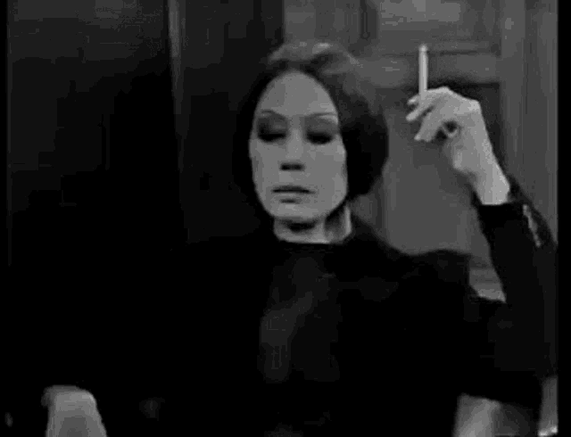 a woman is sitting in a chair smoking a cigarette .