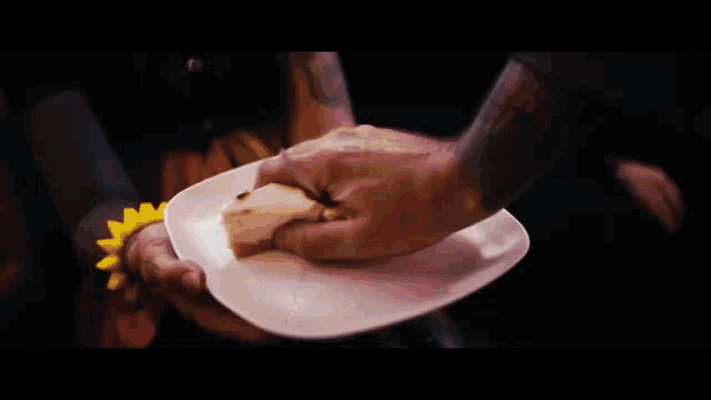 a person with a tattoo on their arm holds a white plate with a piece of bread on it