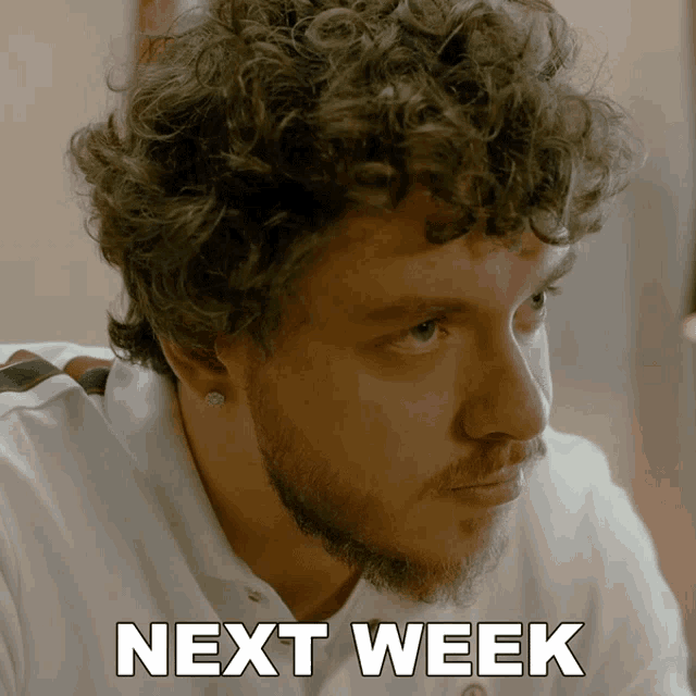 a man with curly hair and a beard has next week written on his face