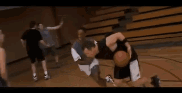 a man is laying on the floor of a basketball court with his legs crossed .