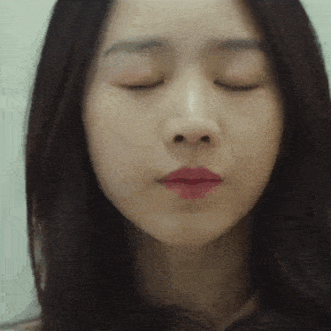 a close up of a woman with her eyes closed .