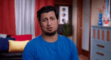 a man in a blue shirt is sitting in a living room with his eyes closed .