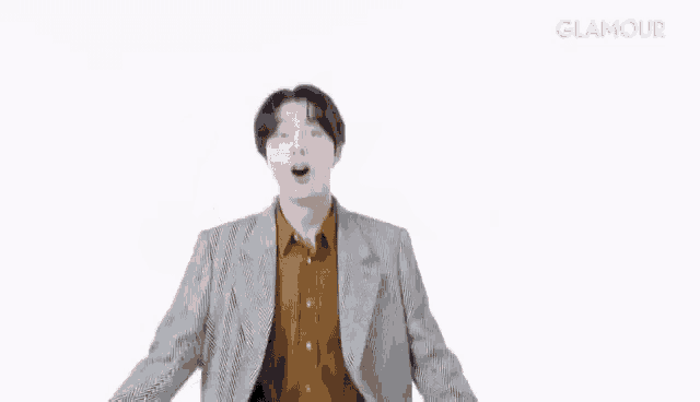 a man in a suit and brown shirt is dancing with his arms outstretched and his jacket open .