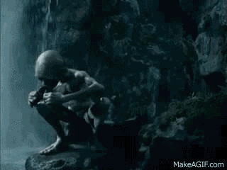 a statue of gollum is squatting down on a rock in a cave .