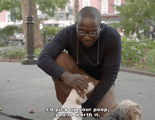 a man is kneeling down with a dog and says i 'd pick up your poop you 're worth it