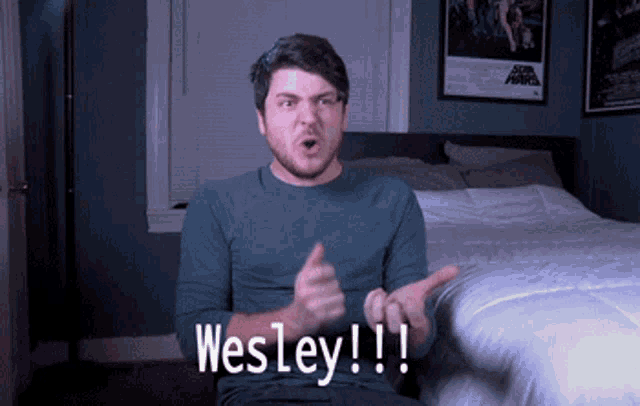a man sitting in front of a bed with the word wesley on his chest