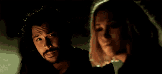 a man and a woman are standing next to each other in the dark .