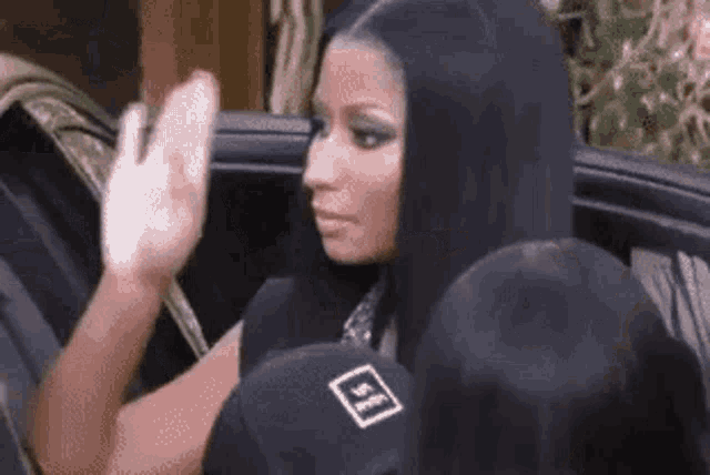 a woman is sitting in the back seat of a car waving .