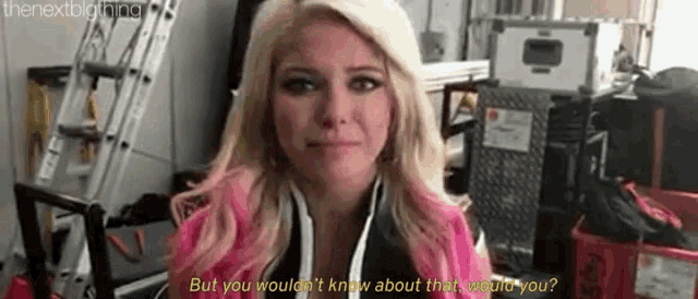 a woman with blonde hair and pink highlights is standing in a room talking to someone .
