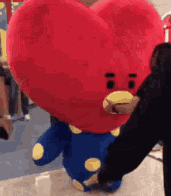 a woman is touching a stuffed animal that looks like a heart .