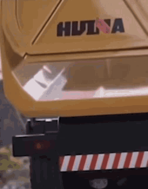 a close up of the back of a yellow dump truck with the word hulna on it .