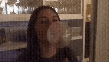 a woman is blowing a bubble in a kitchen