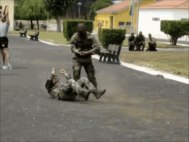 a man in a military uniform is laying on the ground with another man standing behind him