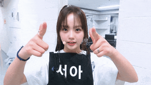 a girl wearing an apron that says ' aoy ' on it giving a thumbs up