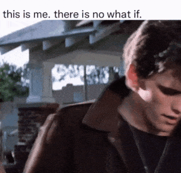 a man in a leather jacket is standing in front of a house and talking to someone .