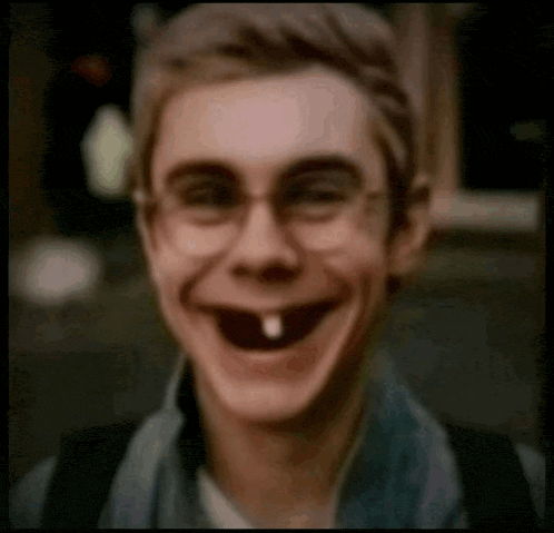 a young man with glasses and a tooth missing is smiling .