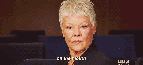 an older woman with short white hair is sitting in a theatre and says on the mouth .