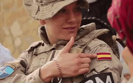 a woman in a military uniform is pointing at a patch on her sleeve