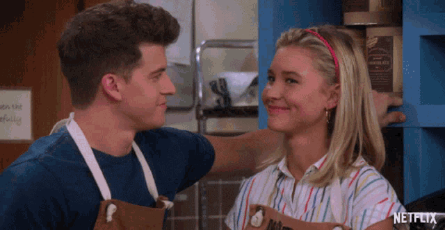 a man and a woman are looking at each other and the woman is wearing an apron that says netflix