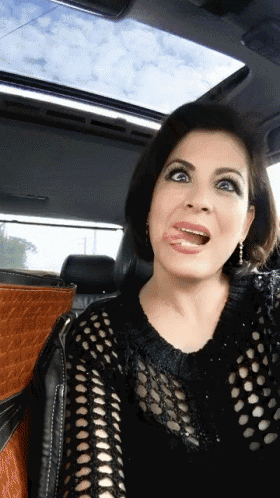 a woman is making a funny face while sitting in the back seat of a car