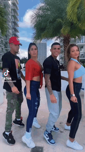 a group of people standing next to each other in front of a palm tree in a city .