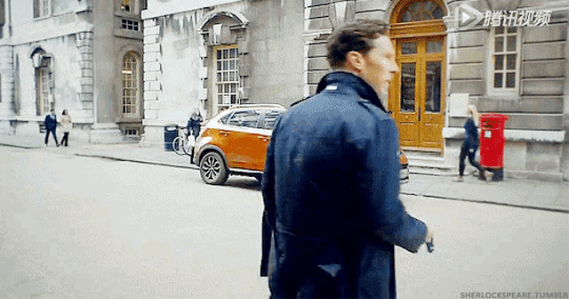 a man in a blue coat is walking down a street in front of a building