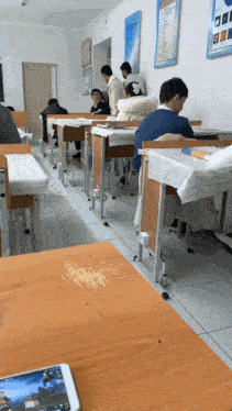 a classroom with people sitting at their desks and a phone on the desk
