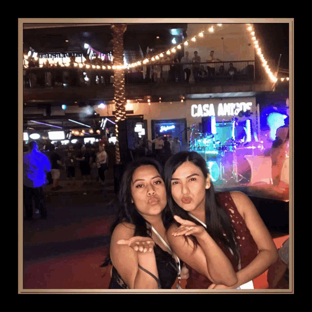 two women pose for a picture in front of a building that says casa amigos