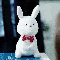 a white stuffed bunny with a red bow tie is sitting on a table