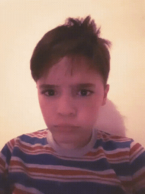 a young boy in a striped shirt is making a funny face