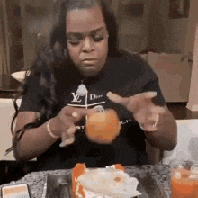 a woman is sitting at a table eating a hamburger .