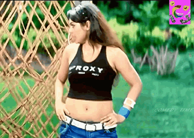 a woman wearing a roxy tank top stands in front of a fence