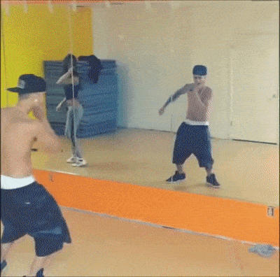 a man without a shirt is dancing in front of a mirror in a dance studio .