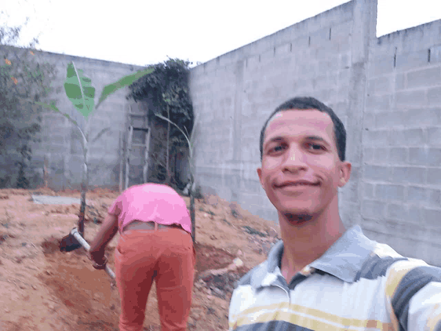 a man in a striped shirt smiles in front of a wall