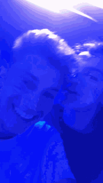a man and a woman are posing for a picture with blue lights behind them