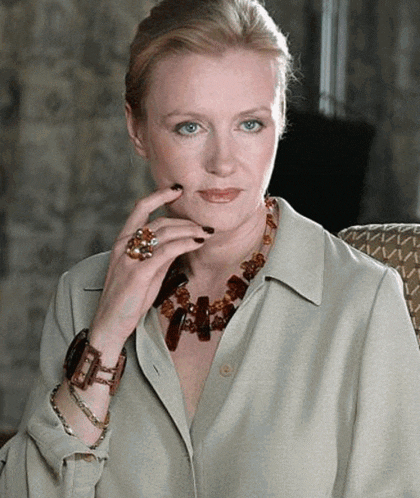 a woman wearing a necklace and a ring is sitting down