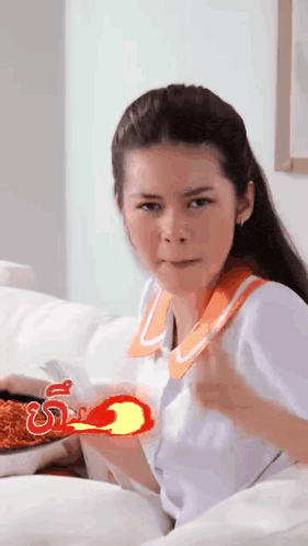 a girl is sitting on a couch holding a red object that looks like a fireball ..