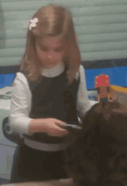 a little girl with a flower in her hair is holding something in her hands