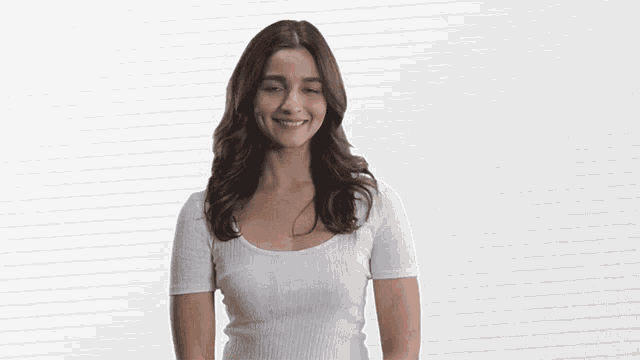 a woman wearing a white shirt is smiling and looking at the camera