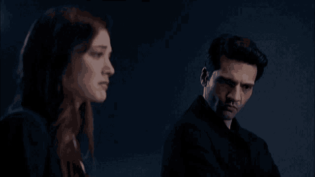 a man and a woman are looking at each other in the dark .