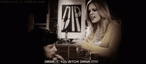 a woman is pouring a drink into a man 's mouth and says `` drink it , you bitch ! ''