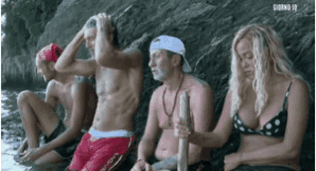 a group of people are sitting in the water and one of them is holding a stick .